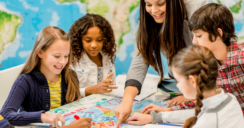 teacher with elementary school children looking at something colorful