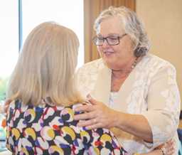 Margaret Stewart embraces Norma Webster, who is facing away from the camera.