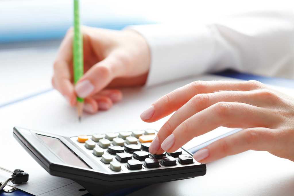 hands using a calculator and taking notes with a bright green pencil